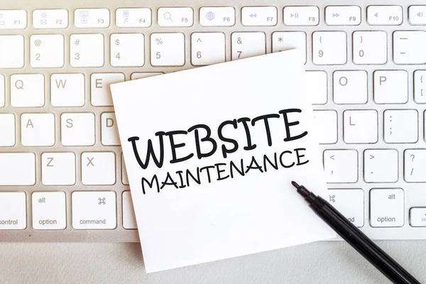 Klavyede siyah keçeli kalemle beyaz arkaplan üzerinde metin web sitesi bakımı olan bir kağıt parçası