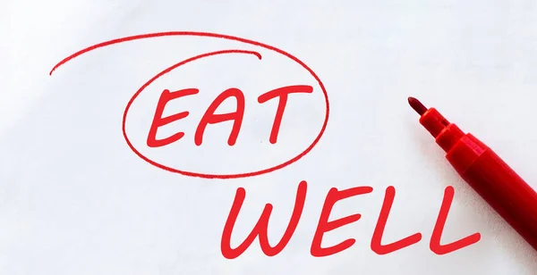 white paper with text Eat Well on the white with red marker