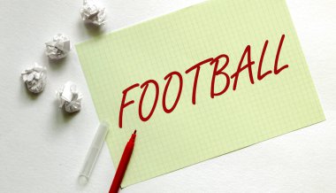Yazılı sarı kağıt. Kırmızı kalemli beyaz futbol topu.