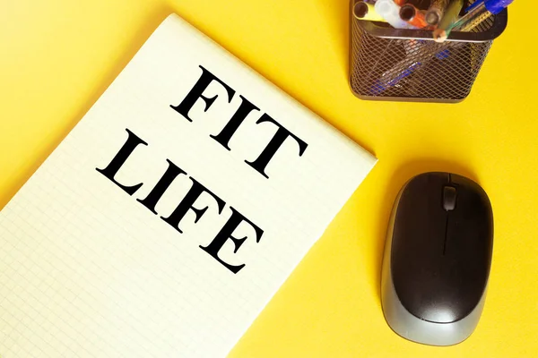 computer mouse, pens, felt-tip pens, notepad with text Fit Life on a yellow background