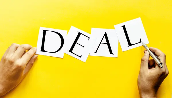Wit Papier Met Tekst Deal Een Gele Achtergrond Met Mensenhanden — Stockfoto