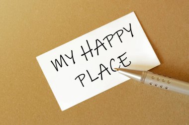 Kalem, beyaz kağıt ve metin. Kahverengi arka plandaki Mutlu Yer 'im.