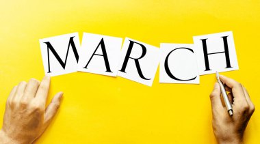 Yazılı beyaz kağıt insan eliyle sarı bir arkaplanda yürür