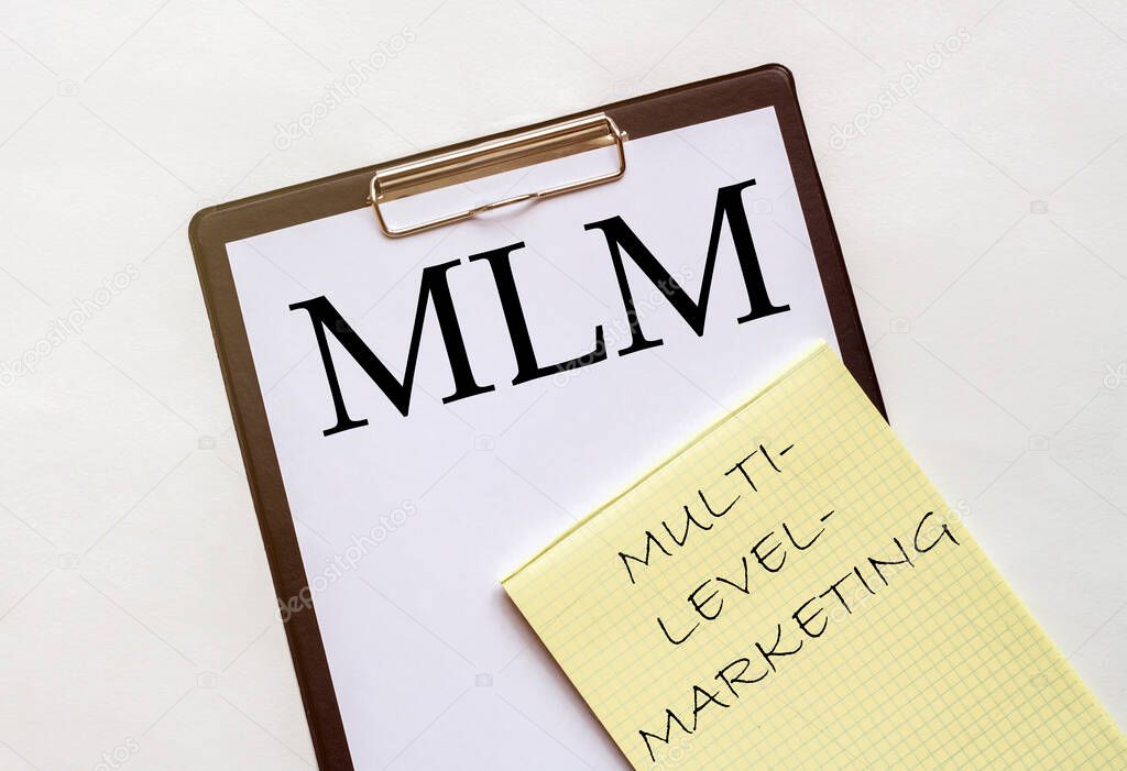 white and yellow paper with text MLM Multi-Level-Marketing on a white background with stationery