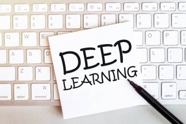 Klavyede siyah keçeli kalemle birlikte beyaz bir arkaplanda Deep Learning yazan kağıt parçası