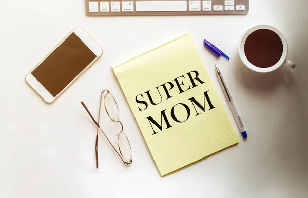 Super Mom text on the yellow paper with phone, coffee, pen