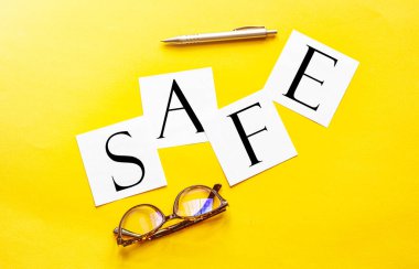 Sarı arka planda, kalem ve gözlüklü, metin korumalı beyaz kağıt.