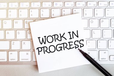 Klavyede siyah keçeli kalemle beyaz arkaplan üzerinde metin çalışması olan kağıt parçası