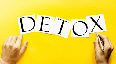 İnsan eli ile sarı bir zemin üzerinde mesaj Detox beyaz kağıt