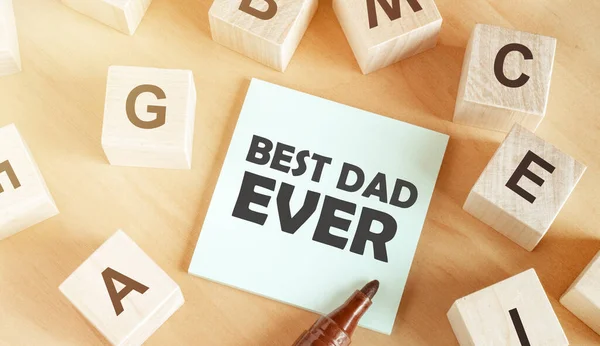 木制立方体 上面有字母字母 一张纸 中间是一张木制桌子 上面写着 最好的爸爸 — 图库照片