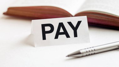 Beyaz bir arkaplan üzerinde kitap, kalem ve arkaplan ödemeleri yazılı kağıt parçası