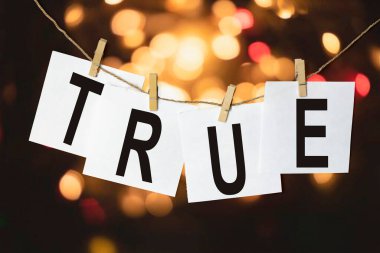 Metni olan beyaz kağıt parçaları Çok renkli bir bokeh arka planına karşı bir ipe asılın