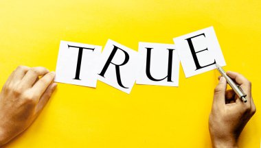 Yazılı beyaz kağıt. Sarı arka planda insan eli ile doğru.