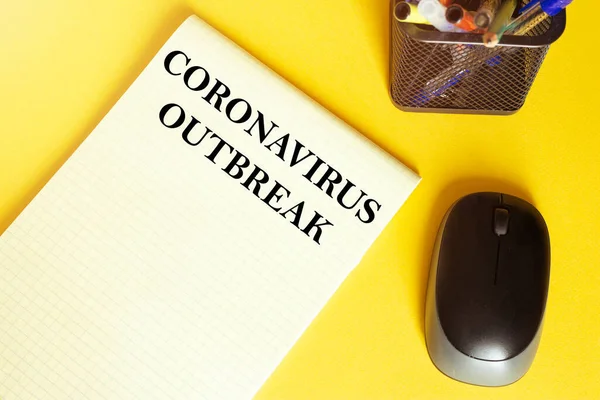 computer mouse, pens, felt-tip pens, notepad with text Coronavirus Outbreak on a yellow background