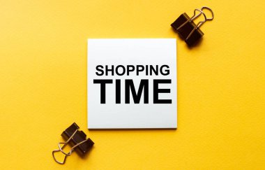 Kırtasiyeli sarı arkaplan üzerinde metin Alışveriş Saati olan beyaz kağıt