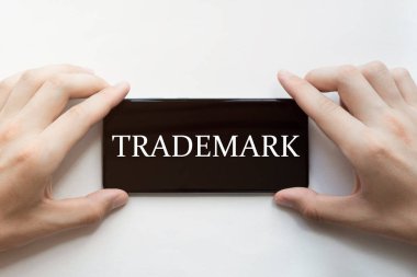 Erkek elleri siyah telefon tutuyor ve beyaz arkaplan üzerinde marka işareti var.