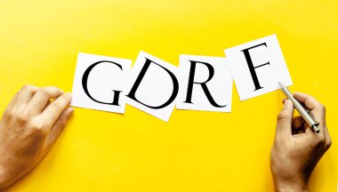 Sarı arka planda insan eli ile GDRF yazılı beyaz kağıt