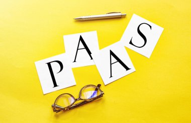 Sarı zemin üzerinde gözlük ve kalemle PaaS Platformu yazılı beyaz kağıt