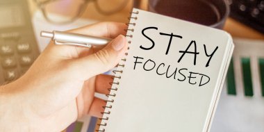 Erkek eli elinde bir defter tutuyor. Üzerinde metin var. Ofis masasının arka planına odaklan.