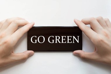 Erkek eller siyah telefonu beyaz arka planda yeşil yazıyla tutuyorlar.