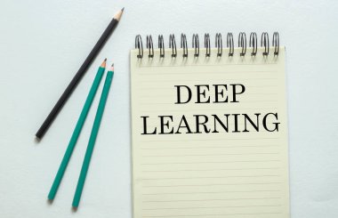 İki yeşil bir siyah kalem ve beyaz arkaplandaki defterde Deep Learning yazıyor.