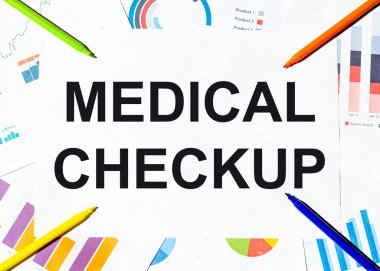 Grafiklerin arka planında tıbbi kontrol metni olan beyaz kağıt parçası, çok renkli keçeli kalemler