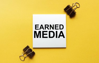 Kırtasiyeli sarı arkaplan üzerinde metin kazanılmış medya içeren beyaz kağıt