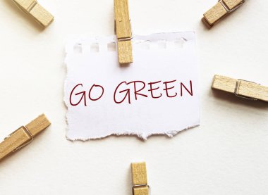 Beyaz arkaplanda çamaşır mandalları ile metinli beyaz kağıt Go Green