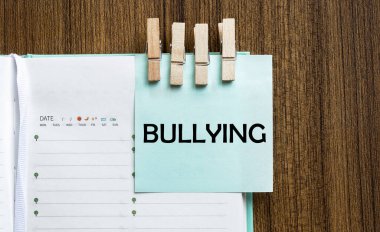 Zorbalık notları ve tahta arka planda elbise askıları.