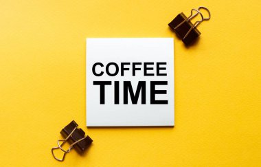 Kırtasiyeli sarı bir zemin üzerinde metin kahve saati olan beyaz kağıt