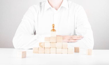 İş adamı kariyer basamaklarını tırmanır. Küpler ve piyonlardan iş konsepti.