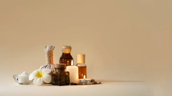 Vacker spa-sammansättning med ljus, frangipani blomma, oljekolv, skål med salt och örtboll. Kopiera utrymme. Stockbild