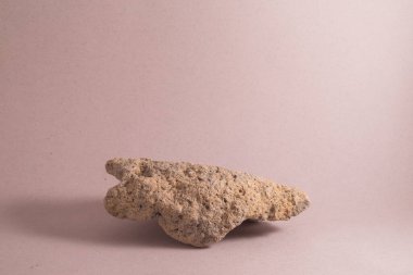 Açık renkli, pembe arkaplanda taş bir podyum.