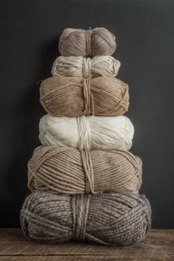 Topraksı tonlarda iplik piramidi. Karanlık bir arka planda doğal iplik..