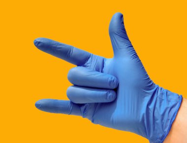 Açık başparmağı, işaret parmağı ve küçük parmağı olan kapalı bir el mavi eldiven ve sarı arka plan. Heavy metal konsepti.