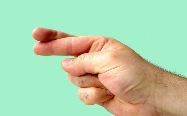 İşaret parmağı ve orta parmağı yeşil arka planda olan kapalı bir el. Şans konsepti.