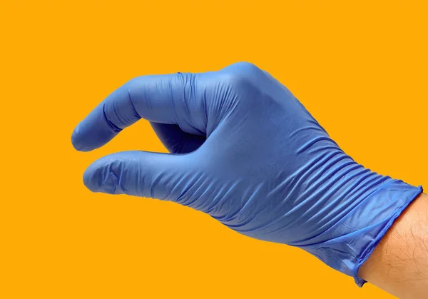 Closed hand with the thumb and index finger slightly open with a blue glove and a yellow background. Concept of small, short, measure