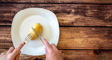 Bıçak ve çatalla kesilen tabakta çiğ bir patates. Seçici odaklanma. Boşluğu kopyala