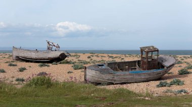 Dungeness sahilinde terk edilmiş iki balıkçı teknesi, İngiltere 'nin Kent sahilinde bir burnu, büyük ölçüde bir kiremit plajı oluşturmuş..