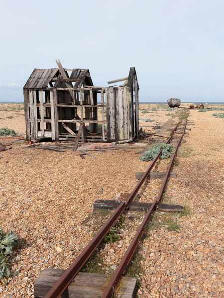 Yünlü bir barakanın akıntıları, dar ölçü rayları ve Dungeness sahilinde terk edilmiş bir balıkçı teknesinin gövdesi, İngiltere 'nin Kent kıyısındaki bir burnu, büyük ölçüde bir kiremit plajından oluşmuştur..