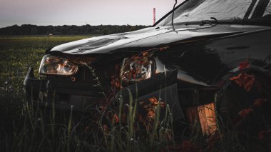 Terk edilmiş modern arabanın önünde.