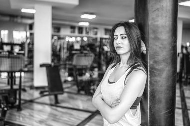 Çapraz kolları üzerinde kum torbası içinde jimnastik salonu yaslanmış olan oldukça sportif kadın