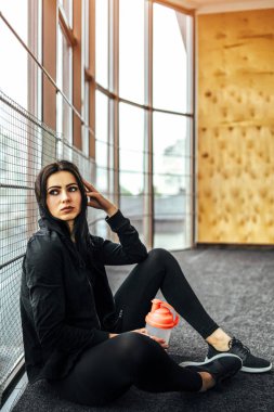 shaker şişe tutan ve salonda otururken kafes penceresinde üzerinde yaslanmış çekici kadın 