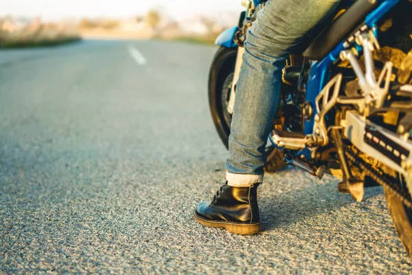 骑自行车坐在运动摩托车上 把腿放在沥青路上 — 图库照片