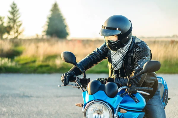 Biker in crash helmet on sport motorcycle on road
