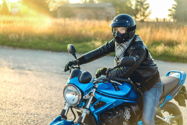 Biker in crash helmet on sport motorcycle on road 