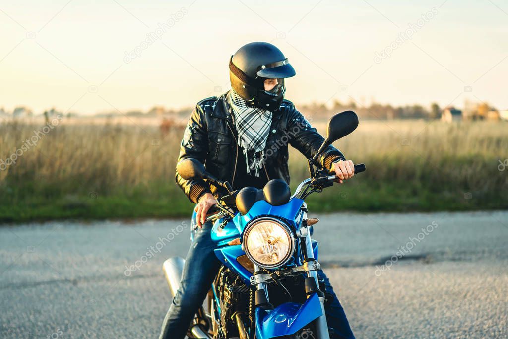 Biker in crash helmet on sport motorcycle on road 