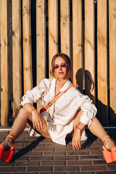Ahşap Çit Yakınında Sokakta Oturan Moda Kadın — Stok fotoğraf