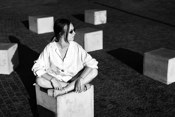ストーン キューブ屋外に座っているファッショナブルな女性の白黒ビュー — ストック写真