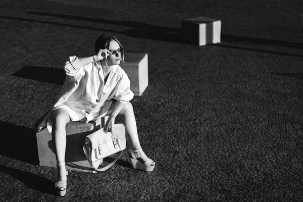 ストーン キューブ屋外に座っているファッショナブルな女性の白黒ビュー — ストック写真